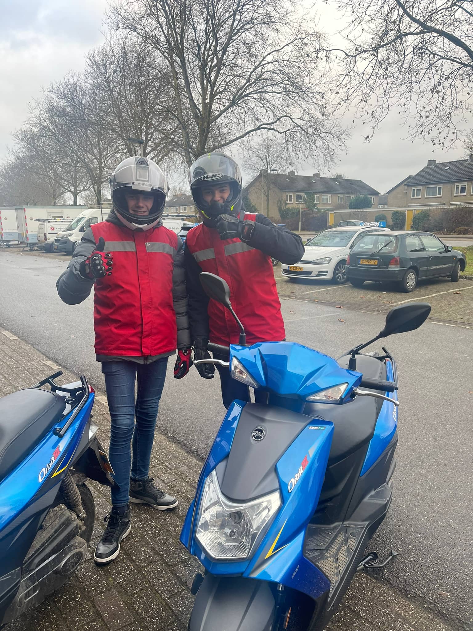 Twee geslaagde bromfietsleerlingen bij de lesscooters van MikDrive